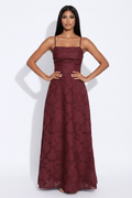 Modelo manos en cadera con vestido largo jacquard burdeos