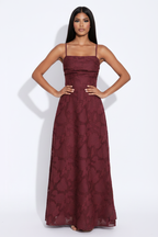 Modelo manos en cadera con vestido largo jacquard burdeos